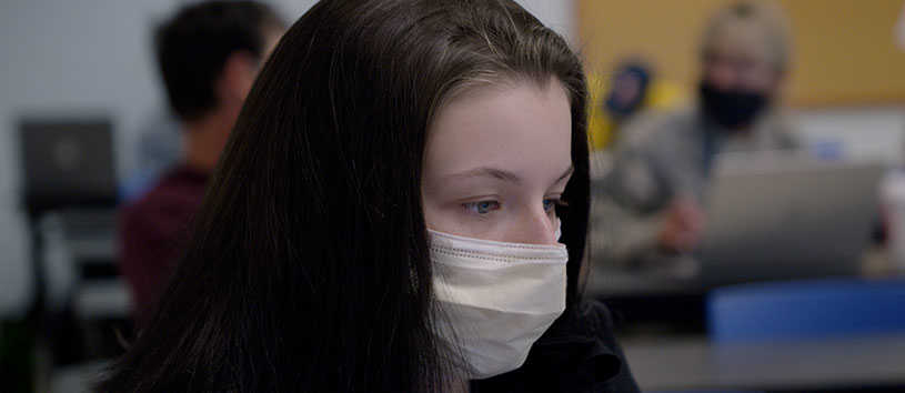 Female student wearing a mask and using a computer.