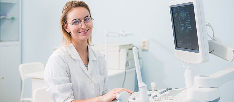 A Health and Science professional sits at a monitor with a variety of medical instruments around her.