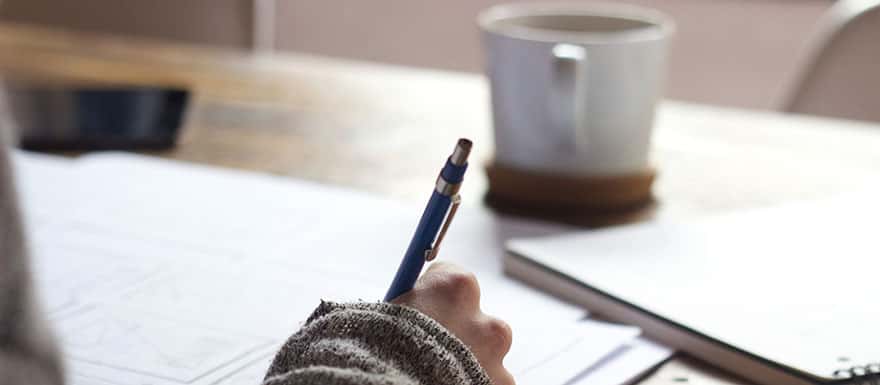 Closeup of a person writing with a pen on paper.